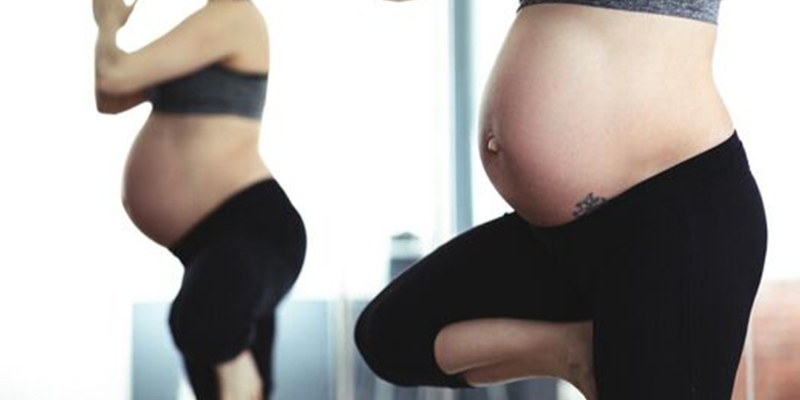 Pregnant woman does a yoga pose in workout gear